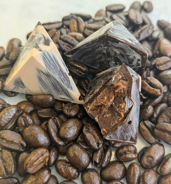 Cubes of dark chocolate on top of roasted coffee beans
