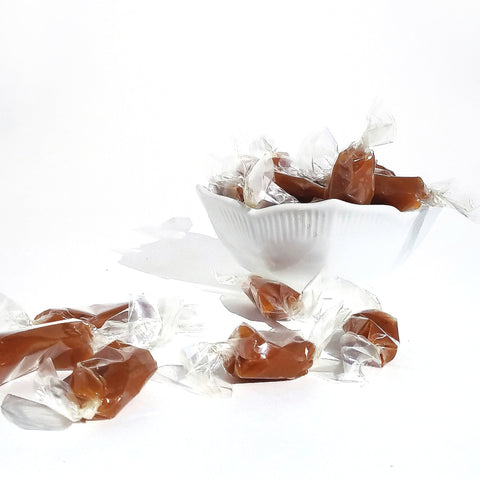 soft caramels spilling out of a white bowl, on a white background
